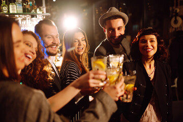 Cheering and drinking cocktails. Group of friends partying in a nightclub and toasting drinks with cocktails. Happy people enjoying winter holiday. Party, celebration, drink, birthday concept.