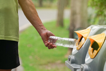 man's hand  throwing plastic bottle into recycle bin.concept for sorting waste in the park, waste separation to protect the environment and reduce global warming.