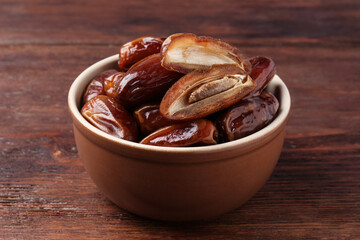 Sweet dried dates in bowl on wooden table, closeup