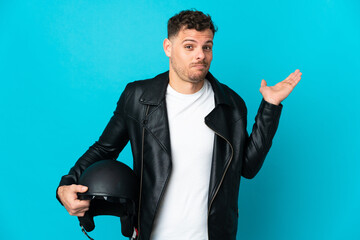 Caucasian man with a motorcycle helmet isolated on blue background having doubts while raising hands