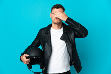 Caucasian man with a motorcycle helmet isolated on blue background covering eyes by hands. Do not want to see something