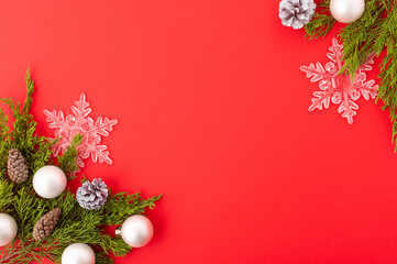 Christmas frame on a red background for your lettering. A beautiful composition - coniferous branches, Christmas balls, openwork snowflakes. New Year, Christmas, postcard, invitation.