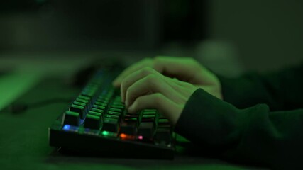 Caucasian Male Hacker Typing on the Keyboard, Trying To Hack the Security System and To Get Data Information From Social Media Accounts. Room Is Lit With Neon Green Colors.
 - Powered by Adobe
