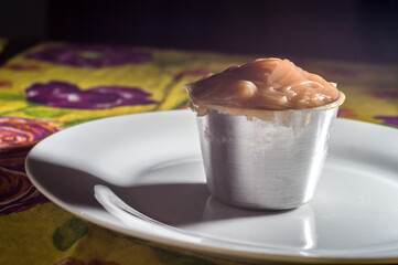 dulce de leche, in a small pot on a white plate, selective focus