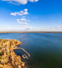 Colorful autumn forest with trees on the shore of a blue lake - top aerial view.