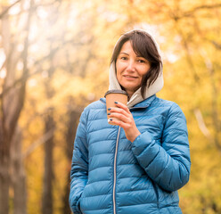 Portrait of a beautiful young woman drinking coffee on a walk