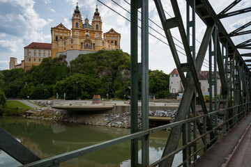 View of the breathtaking 11th century Baroque Abbey (Stift Melk) with views of the Danube River on a rocky outcrop from an iron bridge, Melk, Austria