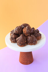 Homemade profiteroles with chocolate. Cream puffs filled chocolate vanilla custard on a bright background. Profiteroles with cream