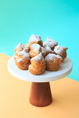 Homemade profiteroles with powdered sugar. Cream puffs filled vanilla custard and dusted with icing on a bright background. Profiteroles with cream and icing sugar.