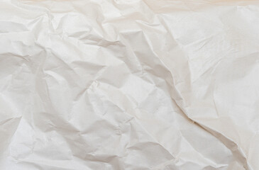 Background texture of crumpled kraft paper. White uneven background. Cracks and creases on paper. Uneven texture.