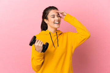 Young sport girl making weightlifting over isolated pink background smiling a lot