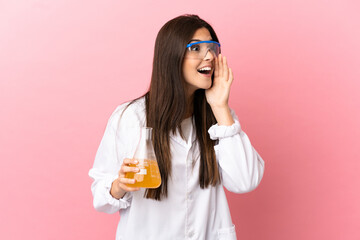 Young scientific girl over isolated pink background shouting with mouth wide open to the side