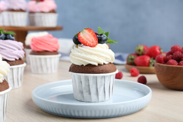 Sweet cupcake with fresh berries on light wooden table
