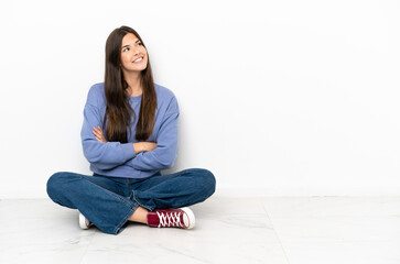 Young woman sitting on the floor looking up while smiling