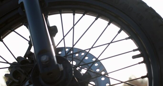 Black bike wheel with new tires and spokes at bright back sunlight against deserted forest extreme closeup slow motion