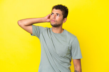 Young handsome Brazilian man isolated on yellow background having doubts