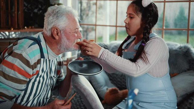 Grandfather and granddaughter eat a heart-shaped pancake together