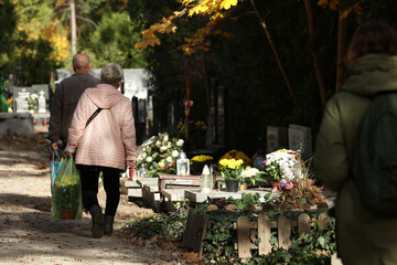 Ludzie odwiedzający cmentarz jesienią w święto zmarłych. 