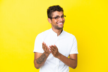 Young handsome Brazilian man isolated on yellow background applauding after presentation in a conference