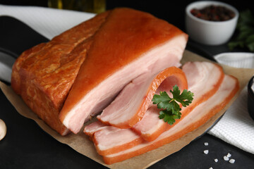 Delicious smoked bacon with parsley and salt on black table, closeup