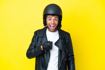 Young Brazilian man with a motorcycle helmet isolated on yellow background with surprise facial...