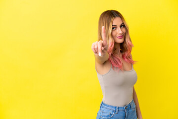 Young woman over isolated yellow background showing and lifting a finger