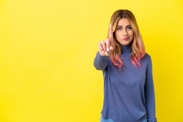 Young woman over isolated yellow background counting one with serious expression