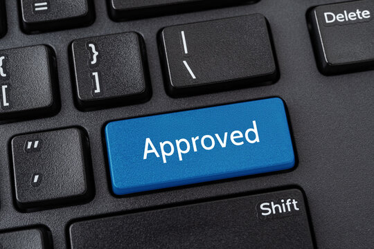 Approved blue key on the black pc keyboard. Concept of business project approval stage. Computer notebook enter key with the word Approved. Message on the enter button of keyboard.