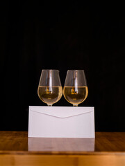 two glasses of white wine and an envelope