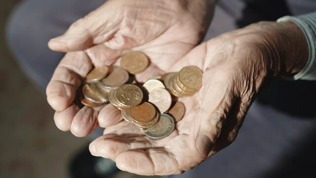 Stack of meager euro coins in hands of old homeless man, abandoned pensioner having no money for survival and existence. Senior poor man begging a helping hand, impoverishment and poverty among old