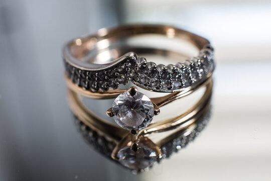 beautiful gold ring with zirconium on a mirror background