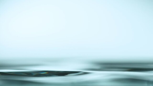Super slow motion of water surface on light blue background. Filmed on high speed cinema camera, 1000 fps.