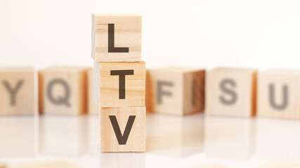 wooden cubes with letters LTV arranged in a vertical pyramid, on the light background, reflection surface, concept