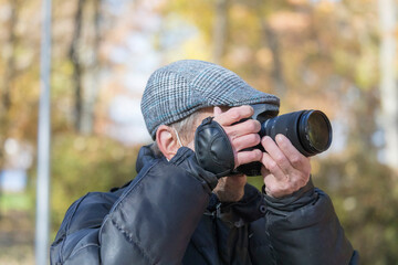 Old man takes pictures of nature in the park