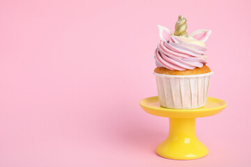 Dessert stand with cute sweet unicorn cupcake on pink background. Space for text