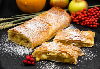 Strudel with apples. A wonderful dessert made of puff pastry. Black background.