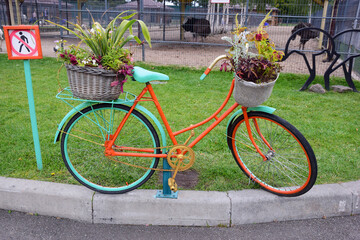 Fototapeta na wymiar A decorative bike on which flower pots with plants are installed standing by the road
