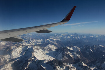 Wing of an airplane over the snowy mountain range.