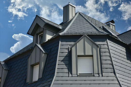 Saniertes Dach mit Stehfalz-Metall verblendeter Gaube und Aluminium-Schindel-Eindeckung auf einem Wohnhaus