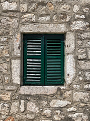 closed green window with shutters in the window opening of an old building or house, a fragment of the facade, texture