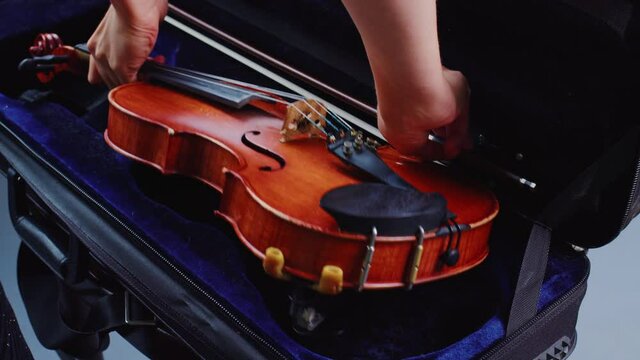Female hands take violin with bow from fiddle case. Violinist pulls out musical instrument before rehearsal, performance or concert. Fiddler, musician woman is going to play melody