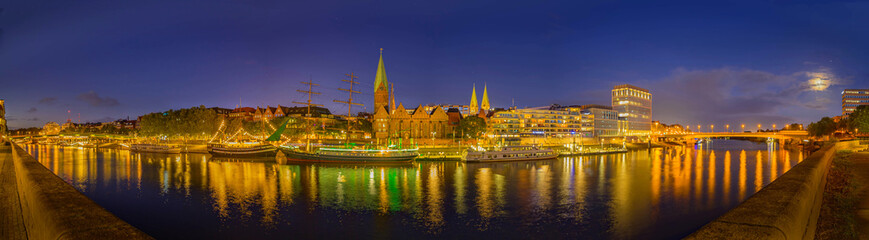 Panorama view of harbour along the Schlachte Embankment and Martinianleger by Bremen. View of Bremen riverside, Weser river, Schlachte promenade by evening. Skyline from Bremen with St. Martini. - obrazy, fototapety, plakaty