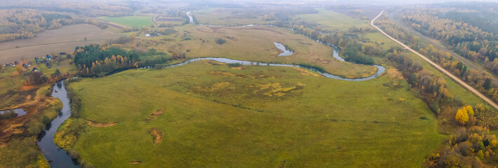 Top view autumn landscape with yellow trees on bank of small river. Nature concept.