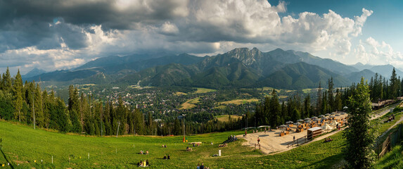 Panoramic view of tourist sitting in nature against sleeping knight tatra mountain covered with dramatic clouds aka as giewont and dramatic clouds located in Zakopane, South Poland, Europe. © Arpan