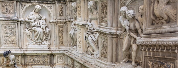 The wall of the old building is decorated with medieval allegorical sculptures