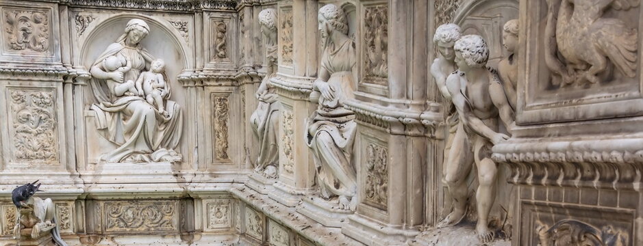 The wall of the old building is decorated with medieval allegorical sculptures