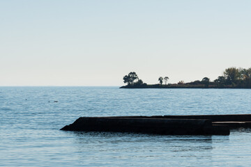 view of jetty with trees and break water and relatively calm lake waters