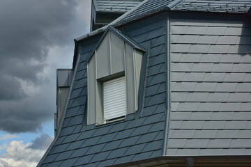 Saniertes Dach mit Stehfalz-Metall verblendeter Gaube und Aluminium-Schindel-Eindeckung auf einem Wohnhaus