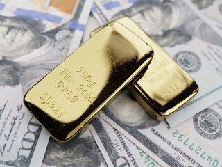 Two fine gold ingots placed on wads of US dollars