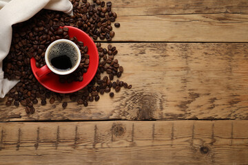 Cup of aromatic hot coffee and beans on wooden table, flat lay. Space for text